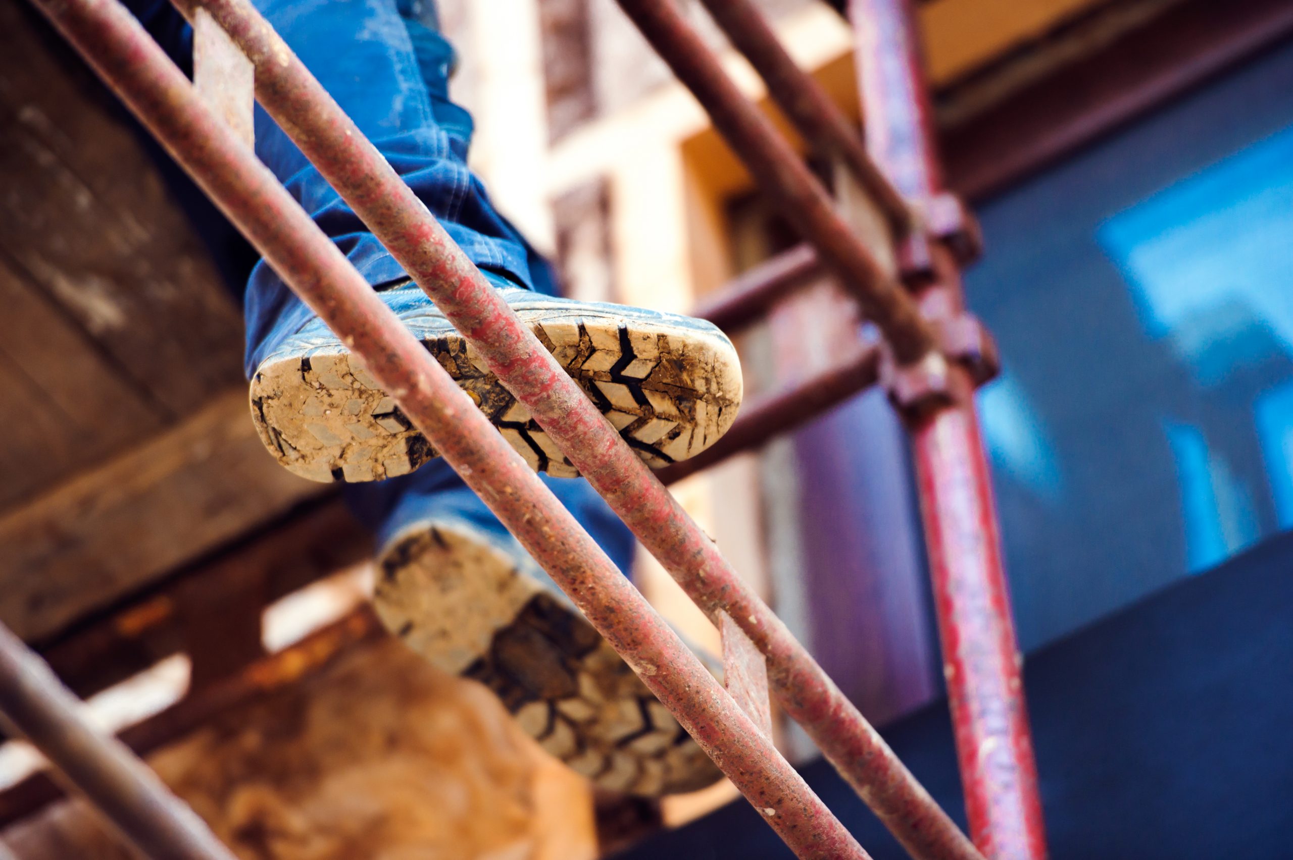 Detail of legs of construction worker standing on scaffolding