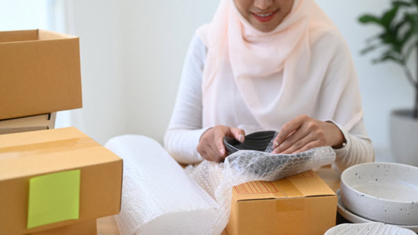 A woman packing a breakable parcel to be delivered to Malaysia
