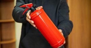A man is holding a fire extinguisher in the office. The concept of fire safety