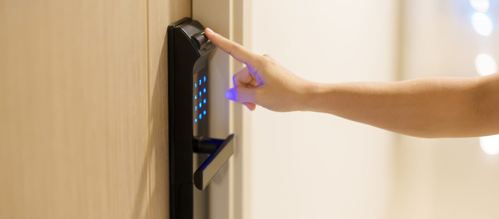 A hand using a fingerprint scanner on a digital smart lock.