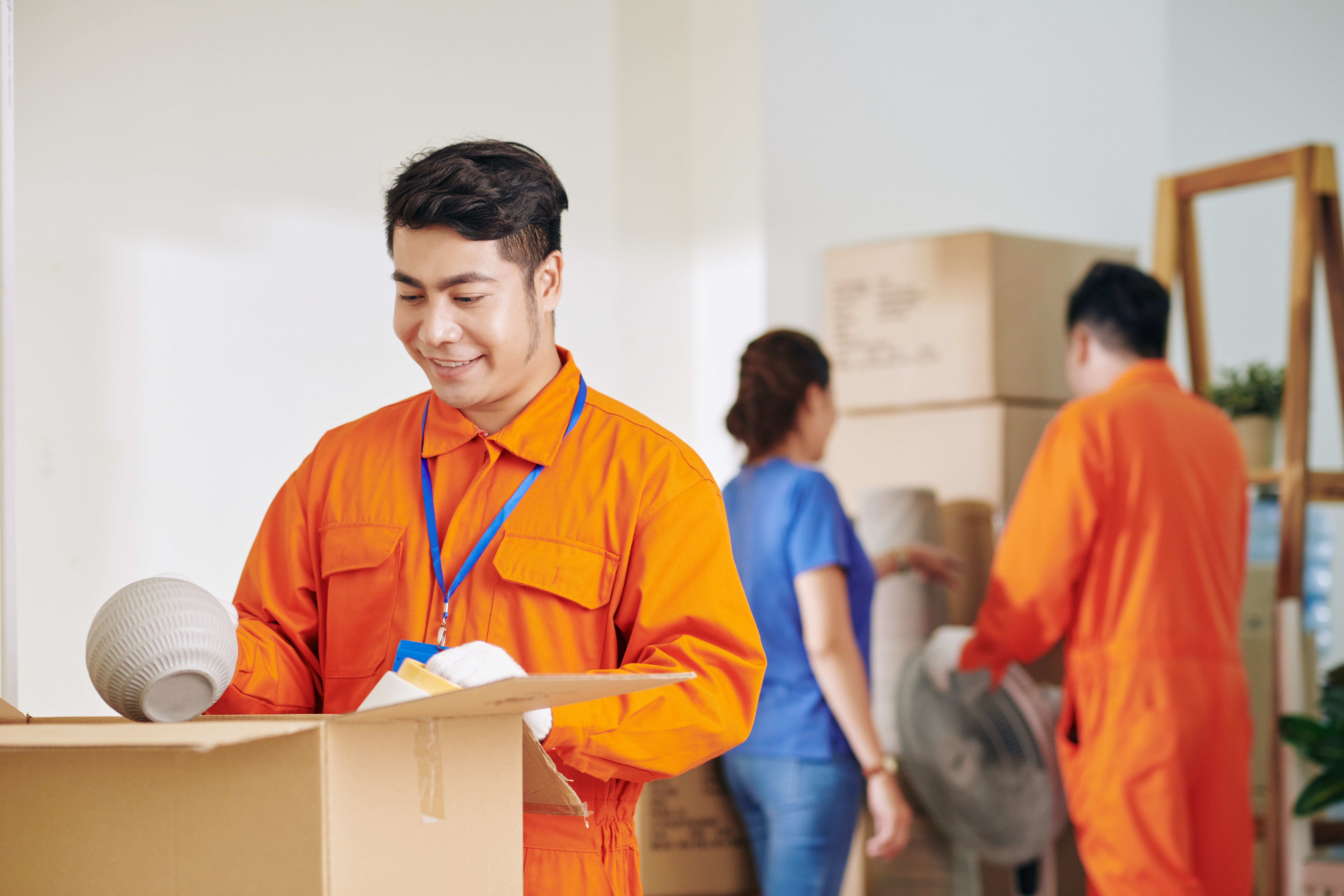 Residential movers in Singapore carefully packing fragile household items
