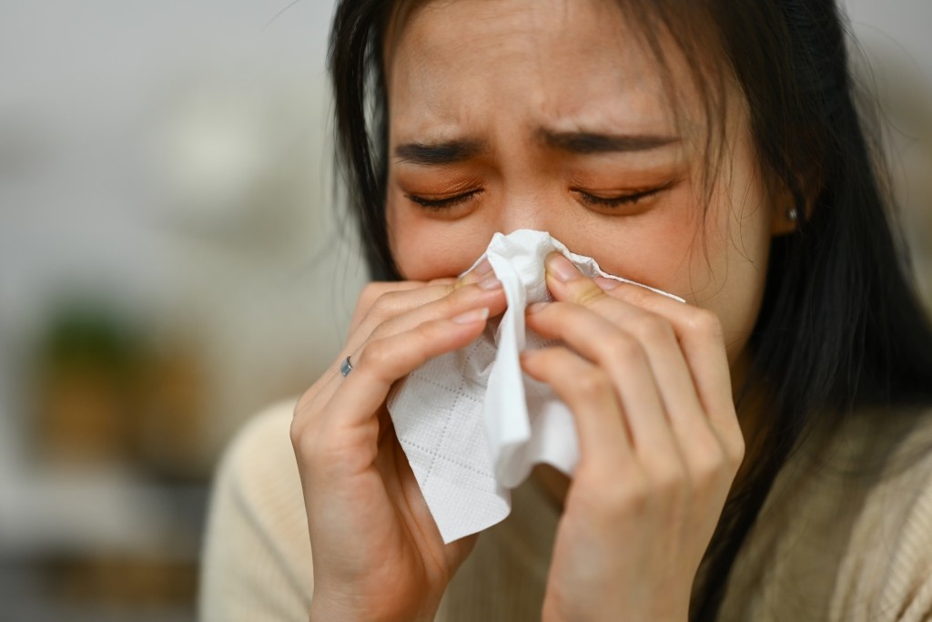 Allergic Rhinitis vs Cold Symptoms Woman blowing her nose and showing signs of nasal allergy symptoms
